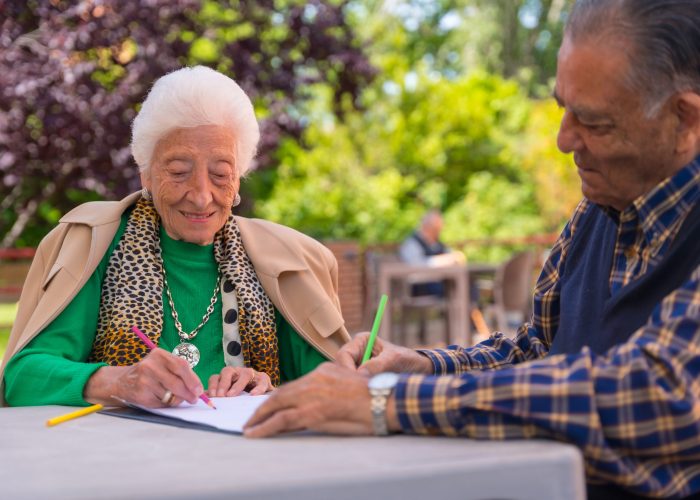 Two elderly people painting in the garden of a nursing home or retirement home